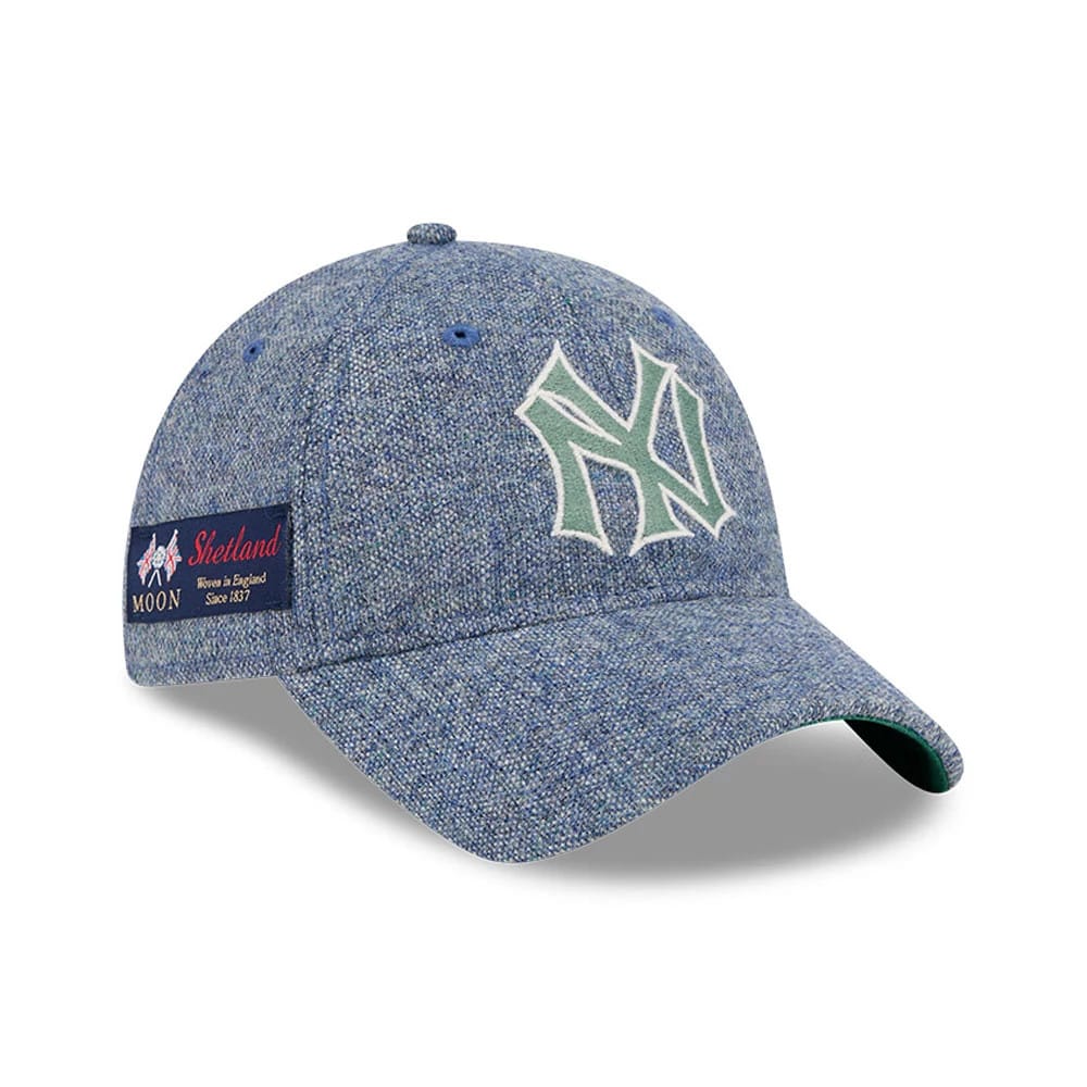 New York Yankees MLB X Moon Blue New Era 9TWENTY Adjustable Cap, three-quarter view showing the white and green embroidered NY logo on the front panel, with a green undervisor and a Moon Shetland woven label on the side.