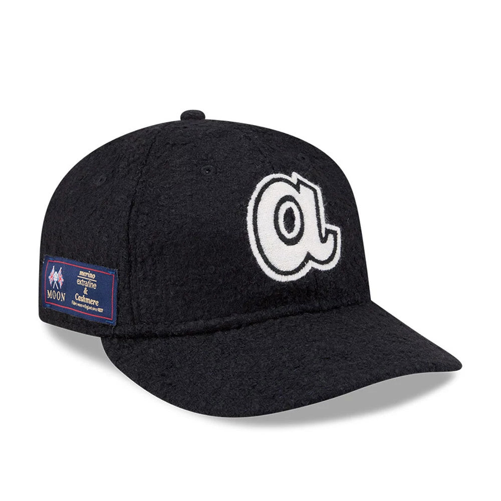 Atlanta Braves MLB X Moon Navy Retro Crown New Era 9FIFTY Adjustable Cap, three-quarter view showing a white embroidered lowercase A logo on the front panel and a Moon merino logo patch on the left side above the visor.