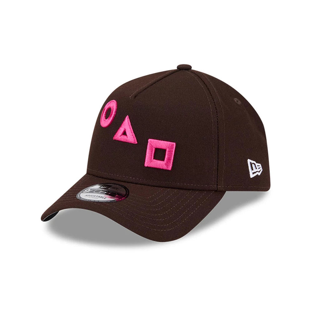 Netflix Squid Game Shapes Dark Brown New Era 9FORTY A-Frame Adjustable Cap, three-quarter view with raised pink embroidered circle, triangle, and square on the front panel, curved visor and white New Era flag logo on the left side.