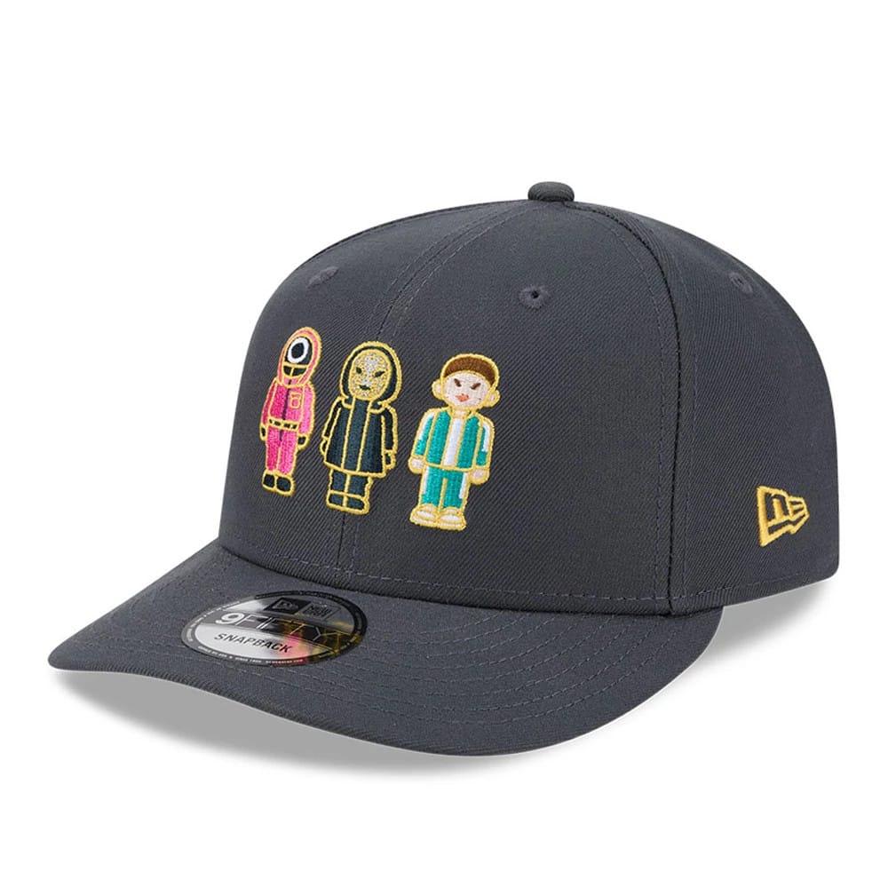 Netflix Squid Game Dark Grey New Era 9FIFTY Snapback Adjustable Cap, three-quarter view showing colourful embroidered character designs on the front panels, a flat dark grey visor with a 9FIFTY size sticker.