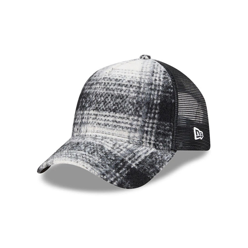 New Era White & Black Plaid 9FORTY A-Frame Trucker Adjustable Cap, three-quarter view showing the monochrome plaid pattern on the front panel and curved visor, with a New Era flag logo on the black mesh side panel.
