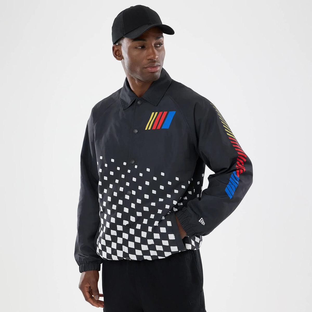 New Era Nascar Logo Black Jacket, on-model view showing the multi-coloured vertical striped logo on the chest and right sleeve, a white checkered pattern across the lower front, and an embroidered New Era logo near the left cuff.