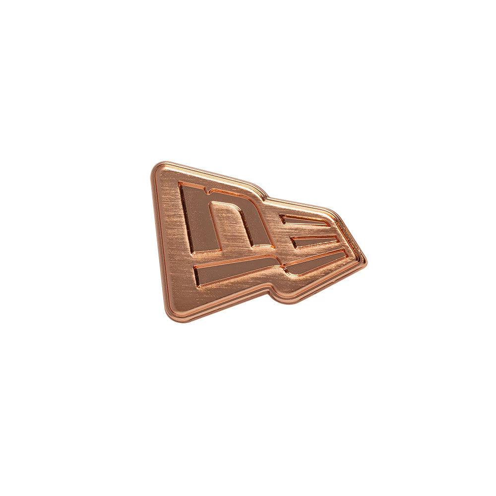 New Era Flag Rose Gold Pin Badge, front view showing the distinctive New Era flag shape with a rose gold finish, highlighting embossed lines creating the brand's logo, with a slight angled perspective for added depth.