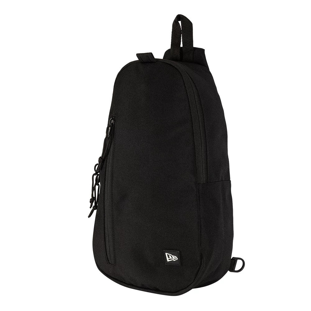 New Era Black Cross Body Sling Bag, three-quarter view showing the black design with a vertical zippered pocket on the front, a top carry handle, and a small white embroidered New Era logo at the lower corner.