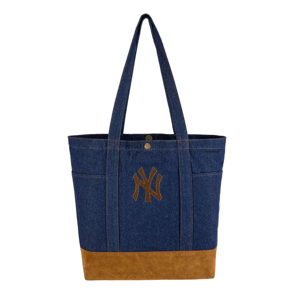 New Era New York Yankees MLB Suede Denim Navy Tote Bag, front view showcasing a navy denim body with a brown suede base, dual long handles, a raised Yankees logo in brown on the front side, and brass button details near the top opening.