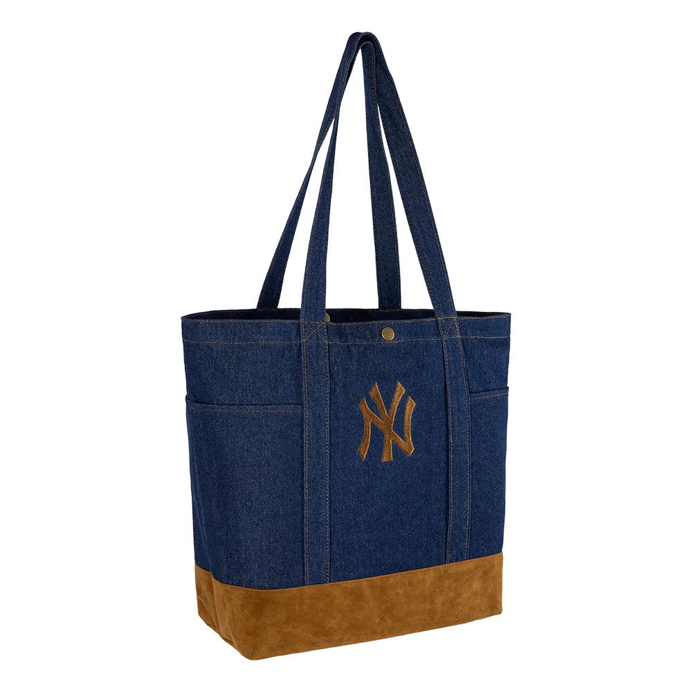 New Era New York Yankees MLB Suede Denim Navy Tote Bag, three-quarter view showing the navy denim body with brown suede base, the embroidered NY Yankees logo centred on the front, and dual shoulder straps extending over the top of the spacious tote.