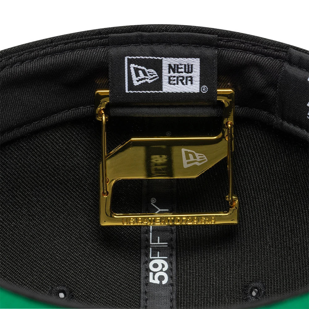 New Era Gold Cap Clip, inside view showing a gold clip attached to the inner band of a cap, with a white New Era flag patch and black taping with 59FIFTY branding beneath it, against a black sweatband.