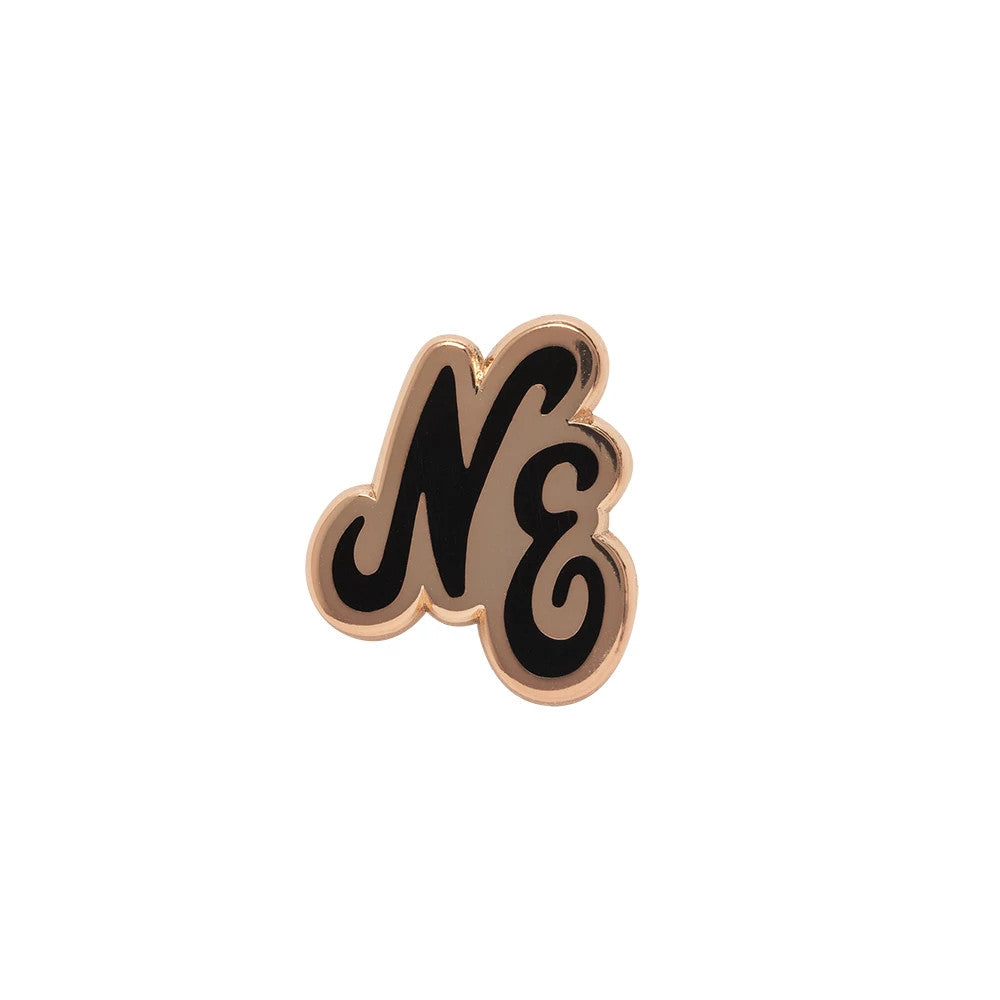 New Era Script Herritage Connect Rose Gold Pin Badge, front view featuring a rose gold pin badge with black script initials NE prominently displayed in a classic font, polished edges highlighting the elegant contrast between the and enamel.