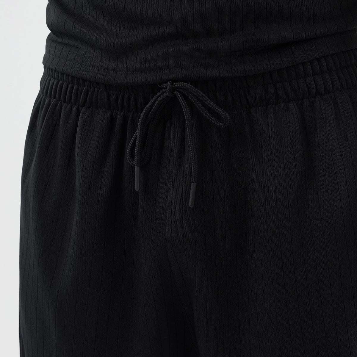 New Era New York Mets MLB Arch Black Oversized Shorts, front view showing the ribbed black fabric with vertical pinstripes, an elasticated waistband featuring a black drawstring, and the matching black top worn above, adding to the coordinated look.