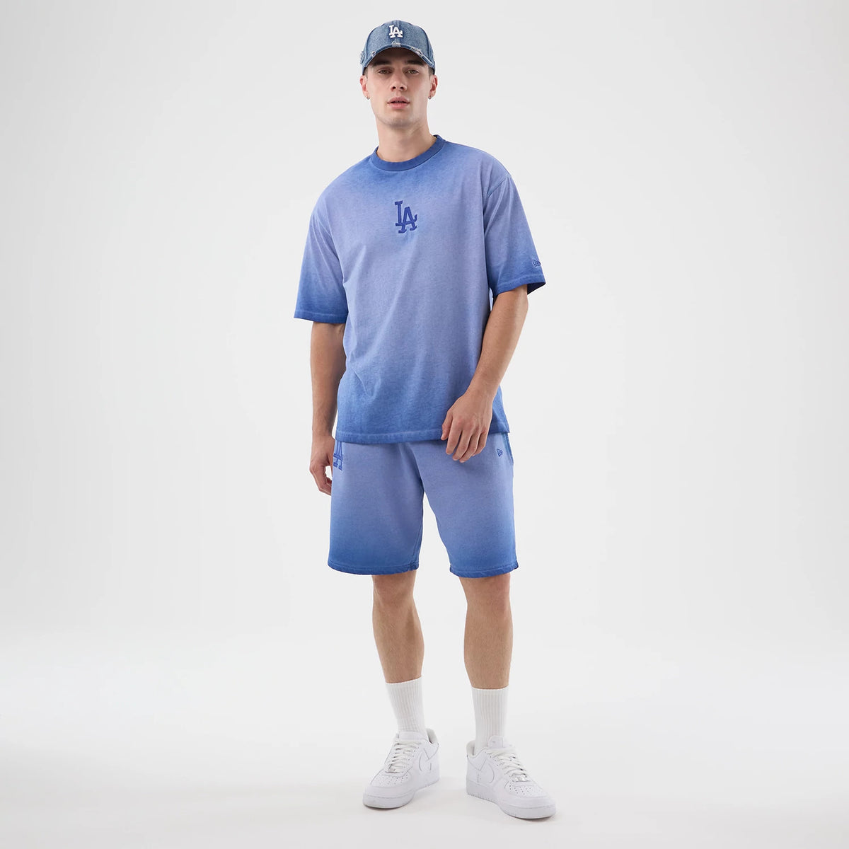 New Era LA Dodgers MLB Washed Logo Pastel Blue T-Shirt, front view on a model styled with matching shorts and cap, featuring an embroidered LA logo in blue on the chest, offering a cohesive and sporty aesthetic with a gradient effect.