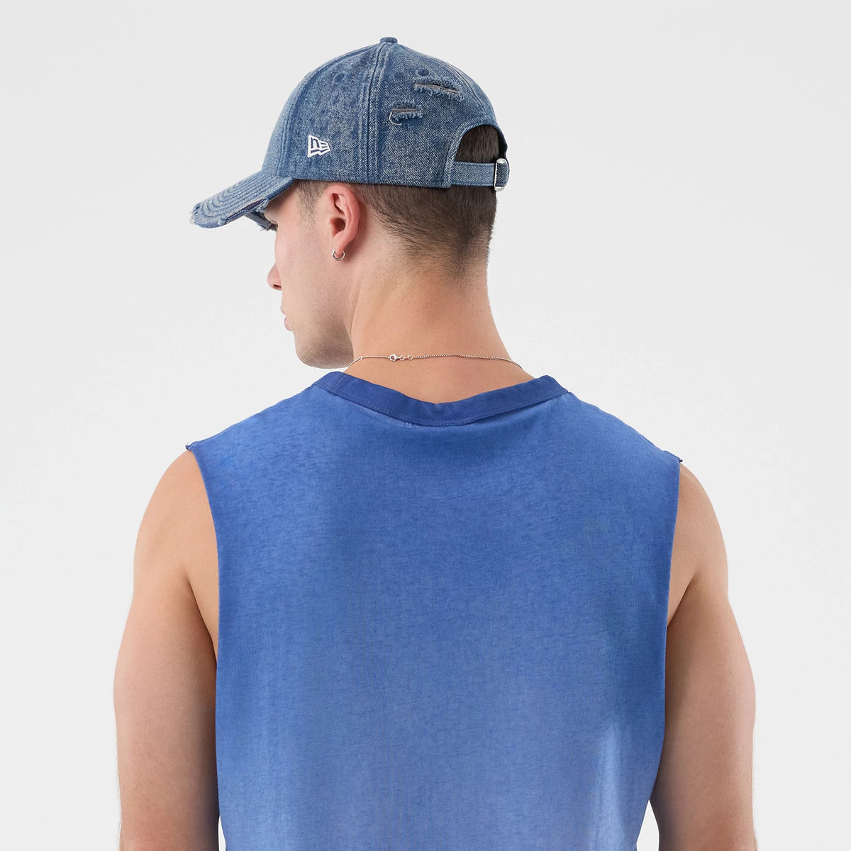 New Era LA Dodgers MLB Washed Logo Pastel Blue Vest, back view on a model showing the sleeveless design and wash effect, paired with a distressed denim cap displaying the New Era flag logo on the left side.