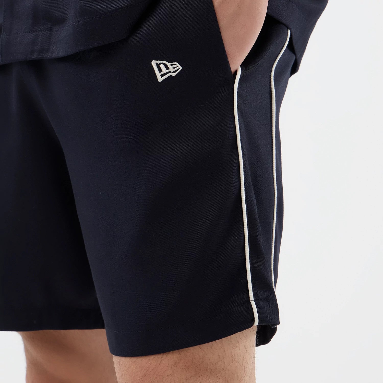 The model is wearing this New Era Piping Shorts in navy. 4