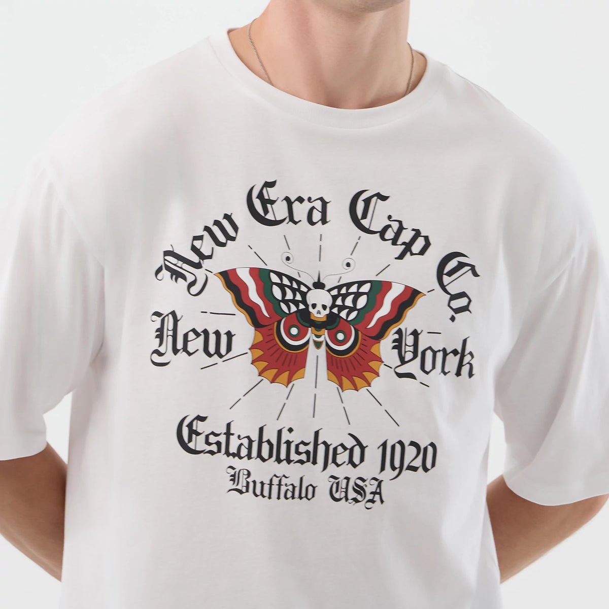 New Era Death Moth Graphic White Oversized T-Shirt, front view showing an intricate coloured moth design with a skull detail in the centre, New Era Cap Co lettering above, and Established 1920 Buffalo USA printed below.