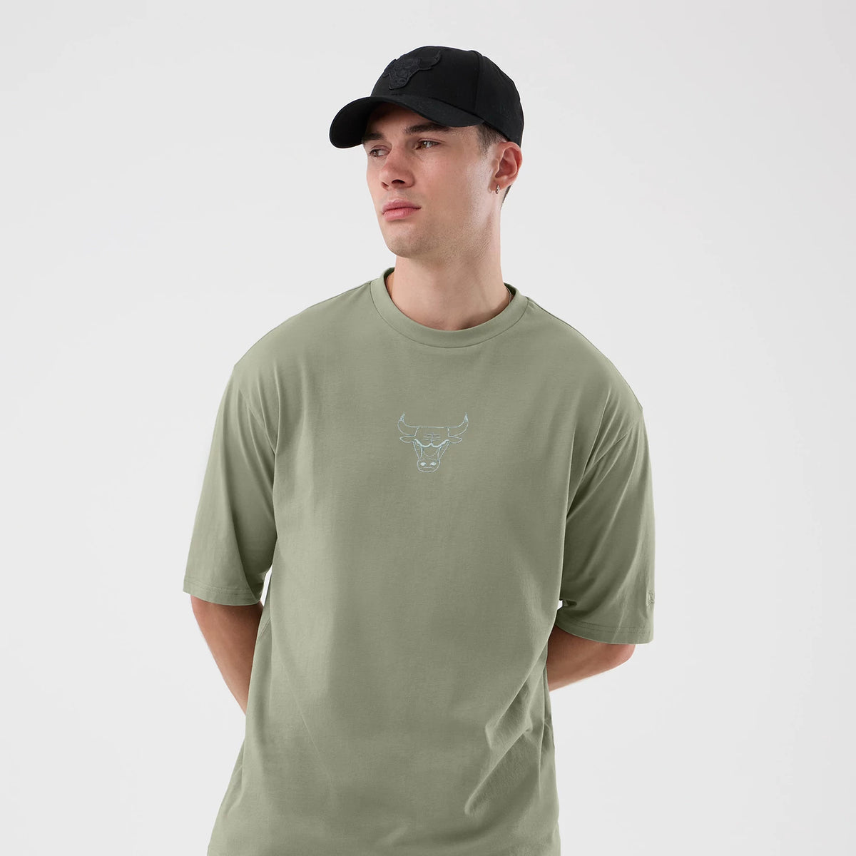New Era Chicago Bulls NBA League Essential Pastel Green Oversized T-Shirt, front view on-model showing the light blue embroidered Bulls logo on the chest, short sleeves and relaxed fit, styled with a black cap featuring a debossed logo on the front.
