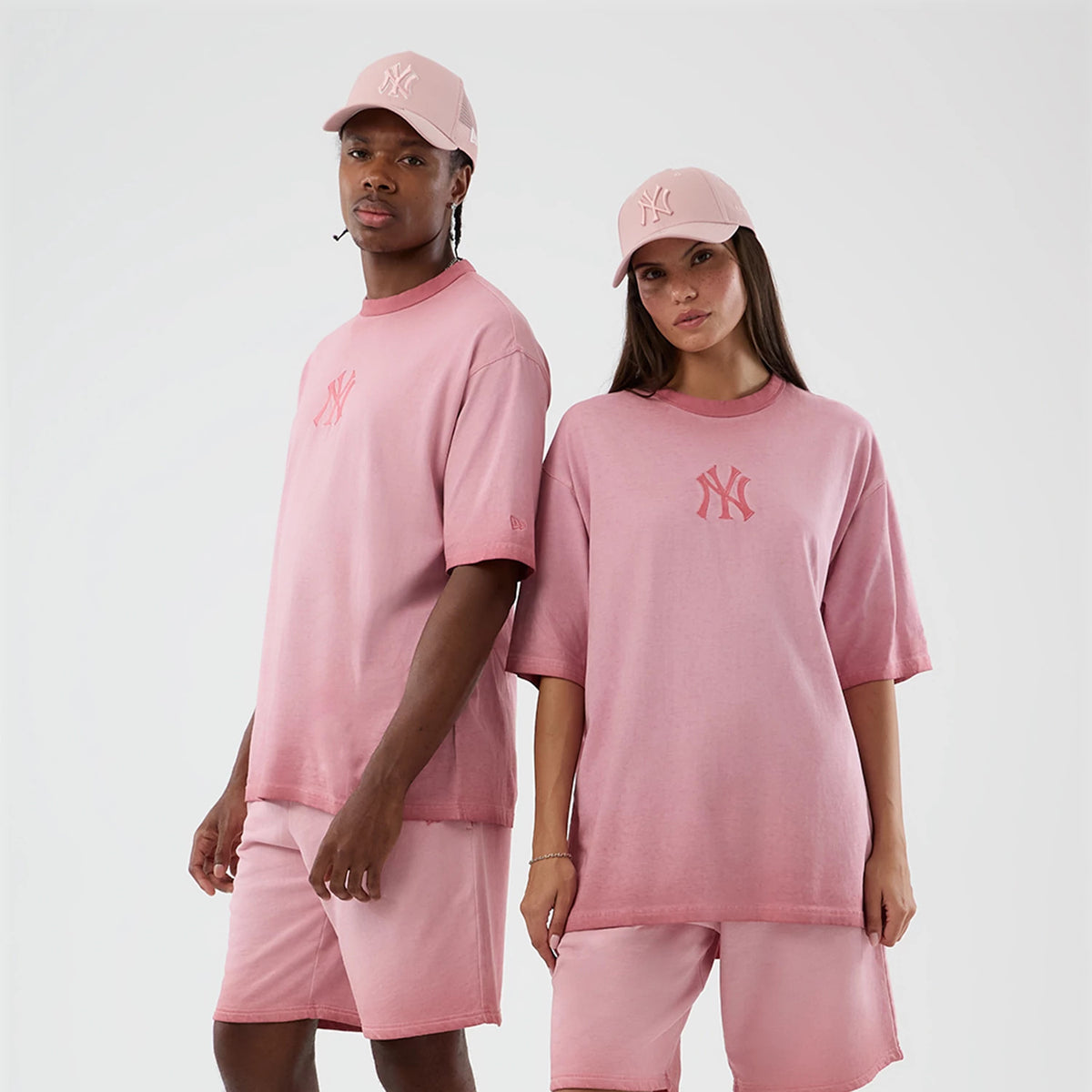 New Era New York Yankees MLB Washed Logo Pastel Pink T-Shirt, on-model view featuring the pastel pink oversized shirt with a slightly faded look, a central embroidered Yankees logo on the front and styled with matching pastel pink shorts and cap.