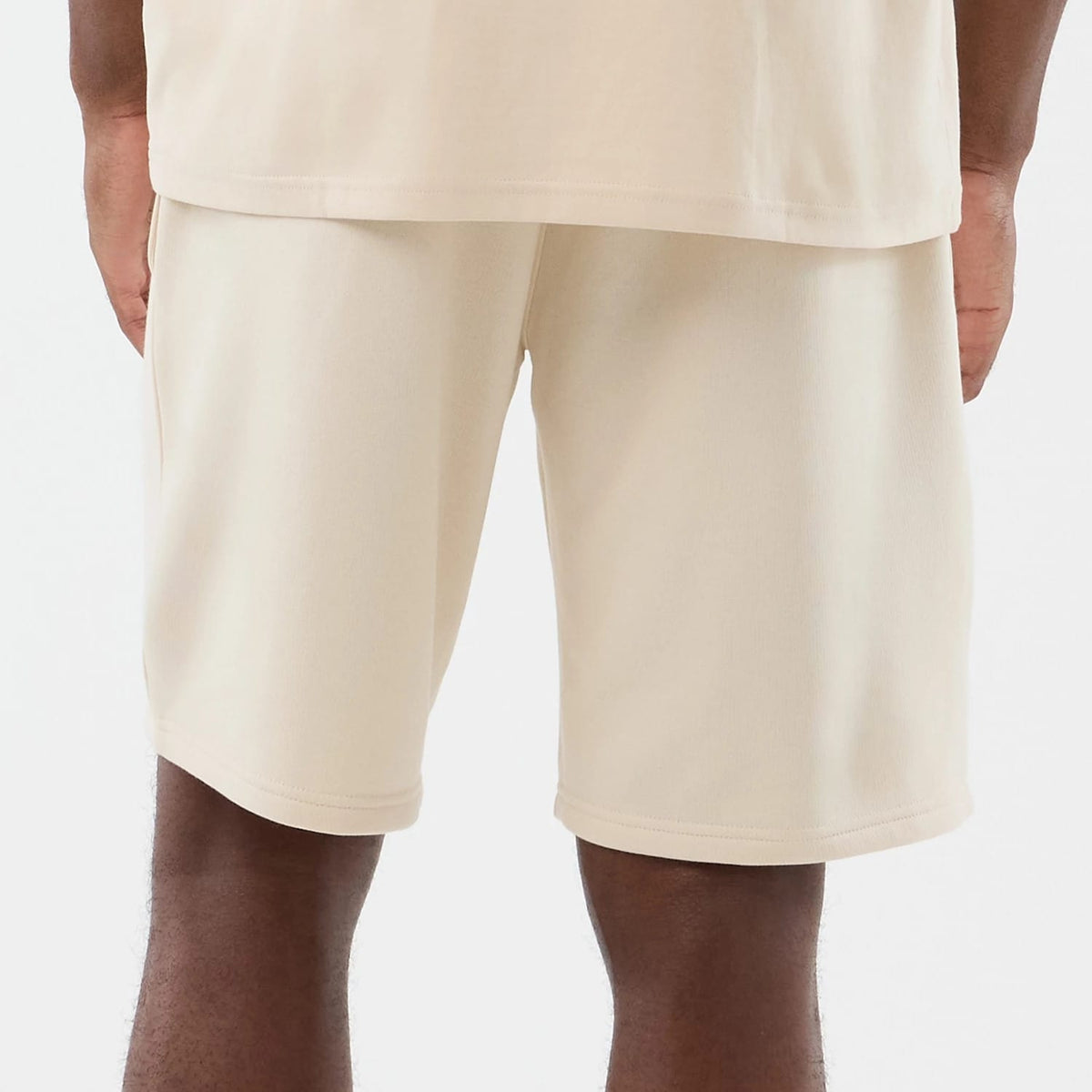 New Era Chicago Bulls NBA Core Plus Light Beige Shorts, back view on a model showcasing a clean light beige finish, knee-length cut, and a relaxed fit, with plain back style and stitching around the hem.