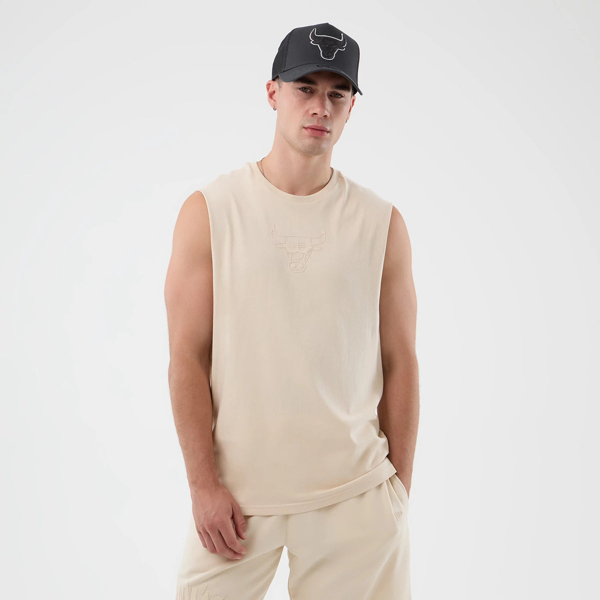 New Era Chicago Bulls NBA Core Plus Light Beige Vest, front view on a model with armholes for ease of movement, featuring an embossed Chicago Bulls logo detail on the chest, matching light beige shorts for a coordinated look.