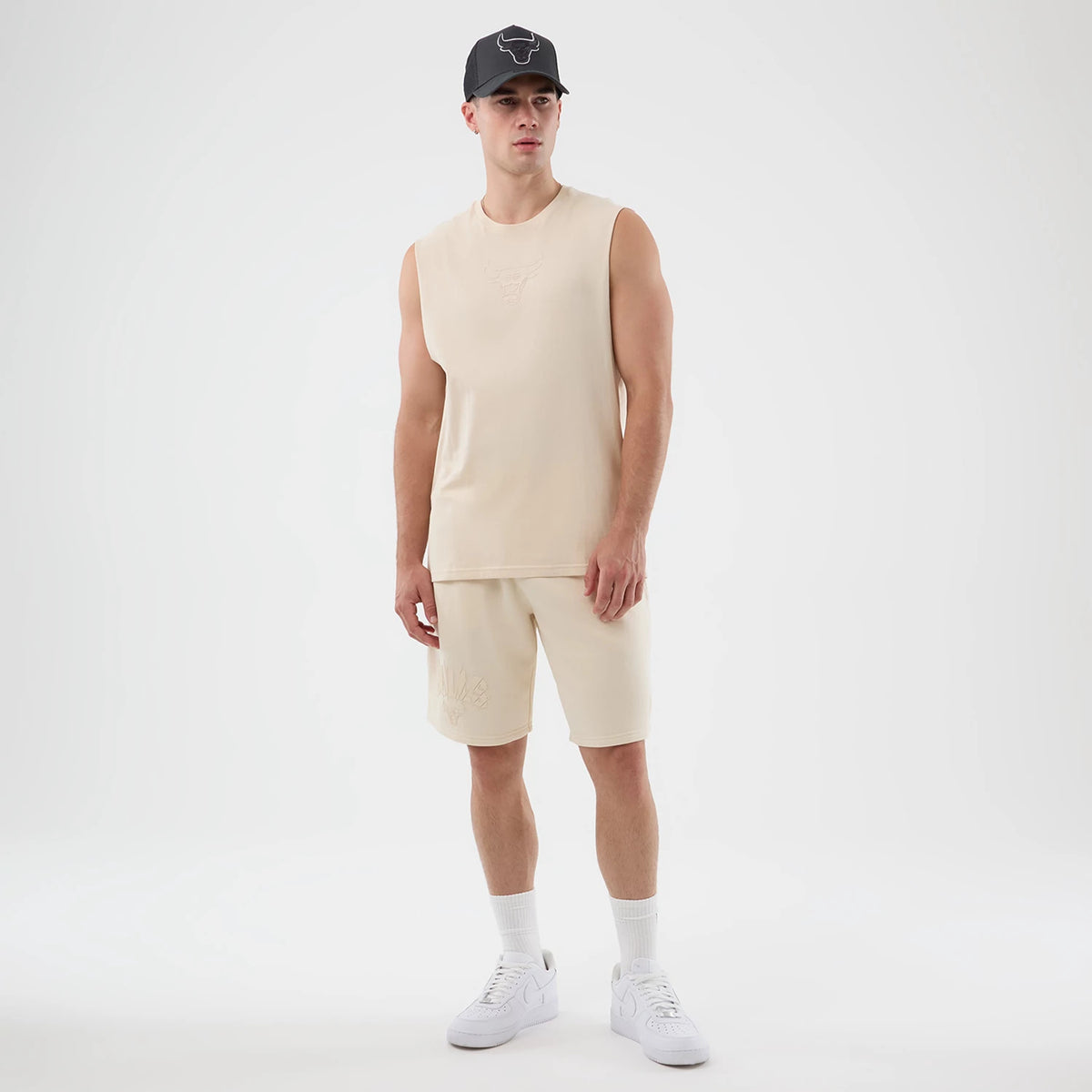New Era Chicago Bulls NBA Core Plus Light Beige Vest, front view on a model with a matching cap, showing the Bulls logo embossed on the chest, the sleeveless design, and a relaxed fit extending to the waist.