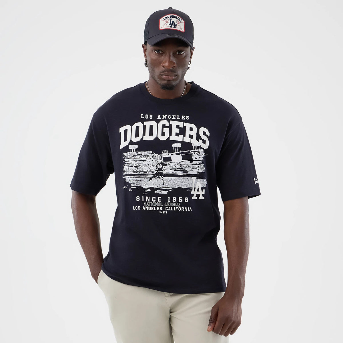 New Era LA Dodgers MLB Slub Navy Oversized T-Shirt, front view on a model showing a Dodgers graphic across the chest with a detailed stadium illustration, Los Angeles lettering above, and an embroidered LA logo near the hem on the side.