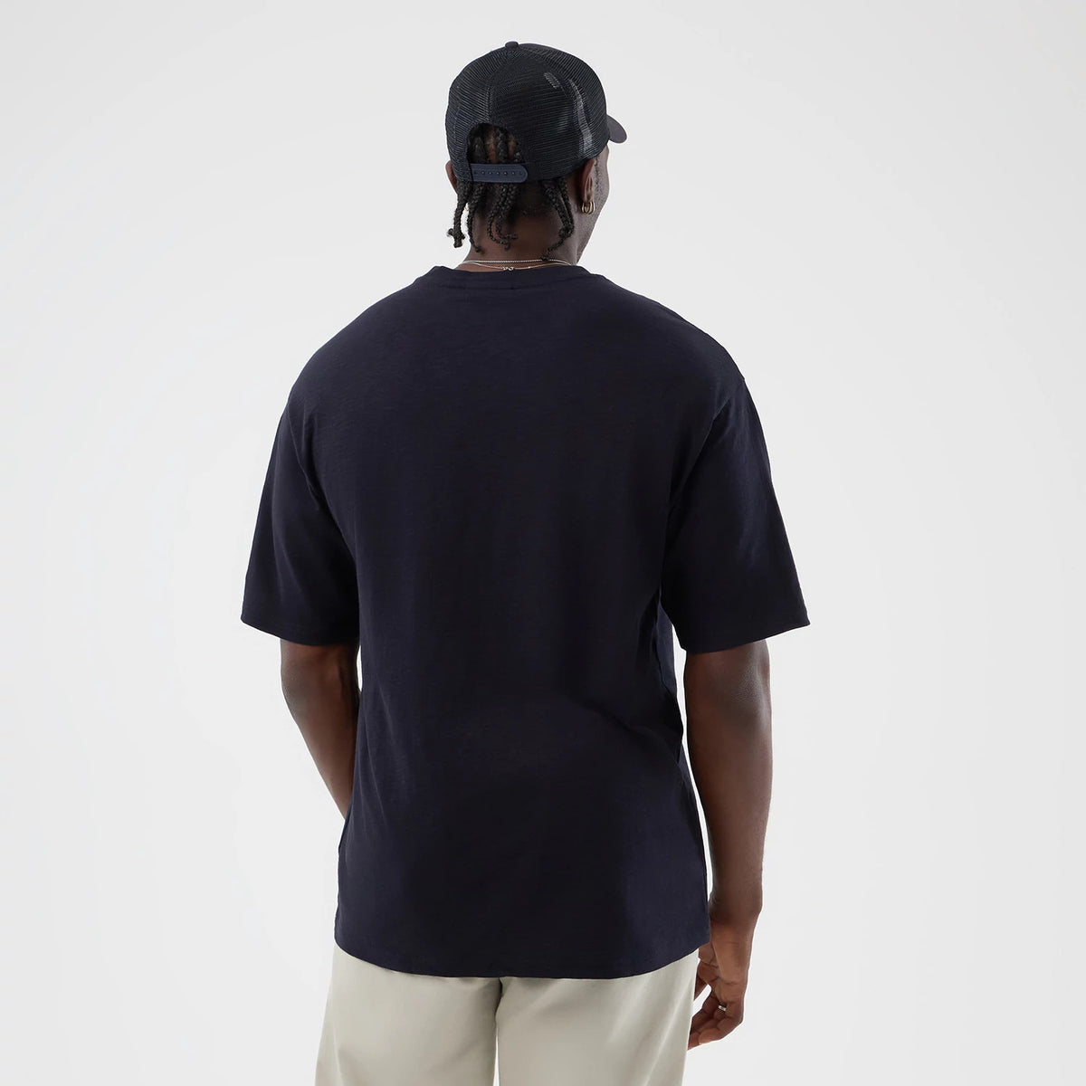 New Era LA Dodgers MLB Slub Navy Oversized T-Shirt, back view on a model paired with light trousers and a dark cap, showing the plain navy design and short sleeves of the oversized fit without any branding or graphics on the back.