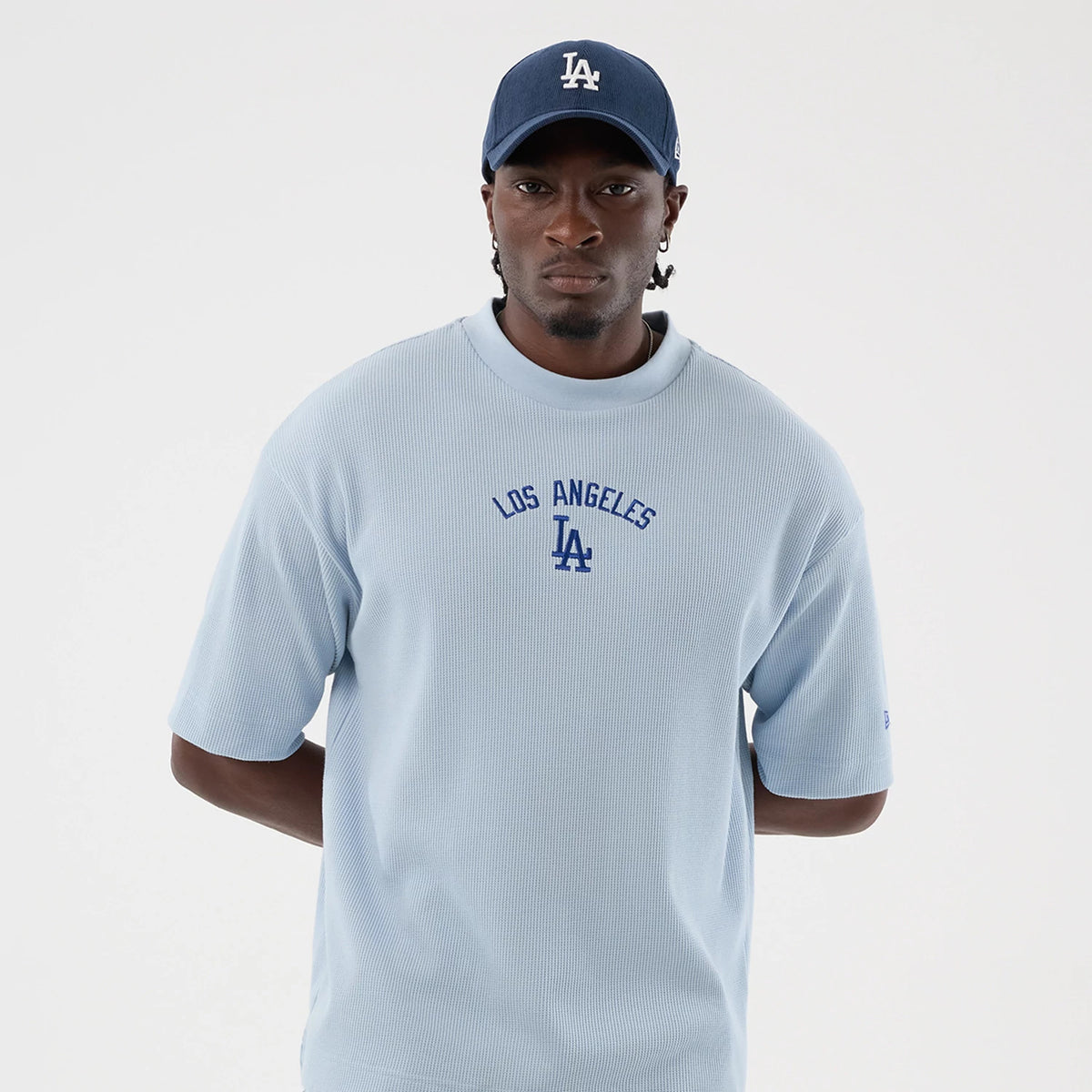 New Era LA Dodgers MLB Waffle Pastel Blue T-Shirt, front view on a model styled with a matching cap, showing the blue embroidered Los Angeles Dodgers logo on the centre chest, short sleeves with a relaxed fit, and ribbed crew neckline.