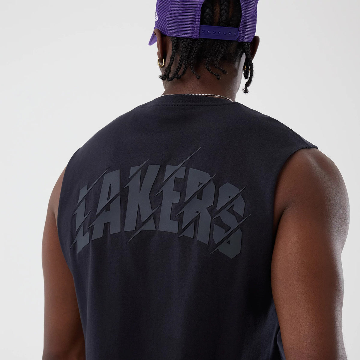 New Era LA Lakers NBA Core Plus Navy Vest, back view on a model wearing a purple cap, highlighting the large grey 'Lakers' lettering across the upper back, sleeveless design, and straight hem.