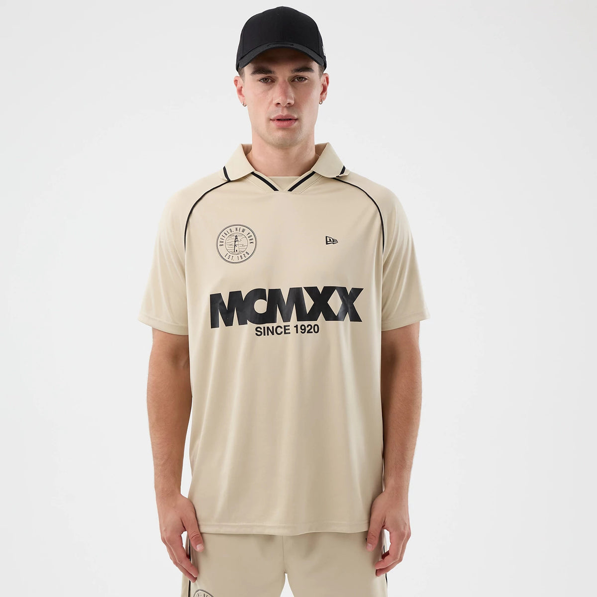 New Era Football Light Beige T-Shirt, front view showing black MCMMX lettering with 'SINCE 1920' across the chest, a circular logo featuring a tower on the left side, and a small embroidered New Era logo on the right side.