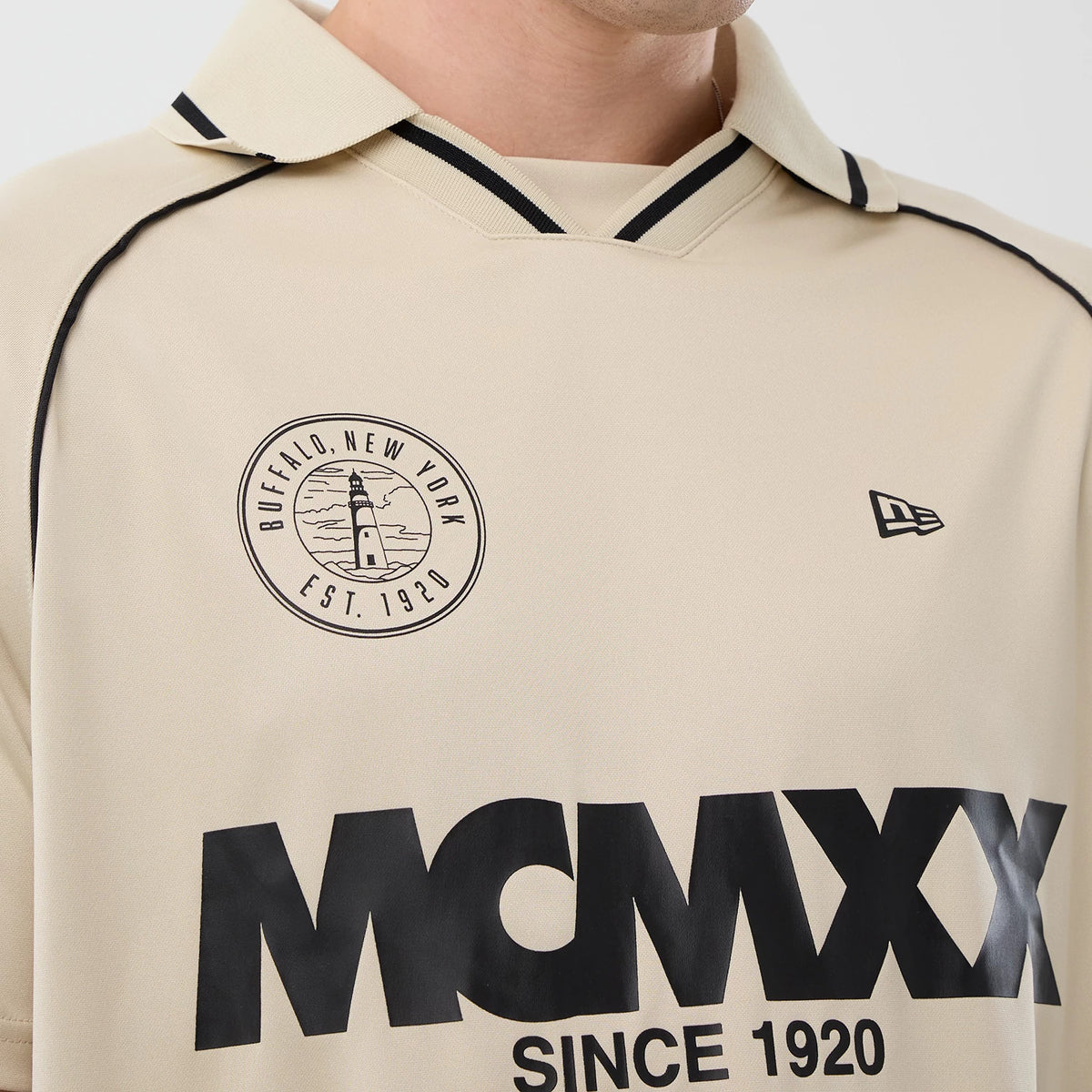 New Era Football Light Beige T-Shirt, front view showing a circular graphic with a lighthouse and BUFFALO, NEW YORK EST. 1920 on the left chest, a black New Era embroidered logo on the right, and MCMXX SINCE 1920 lettering below.