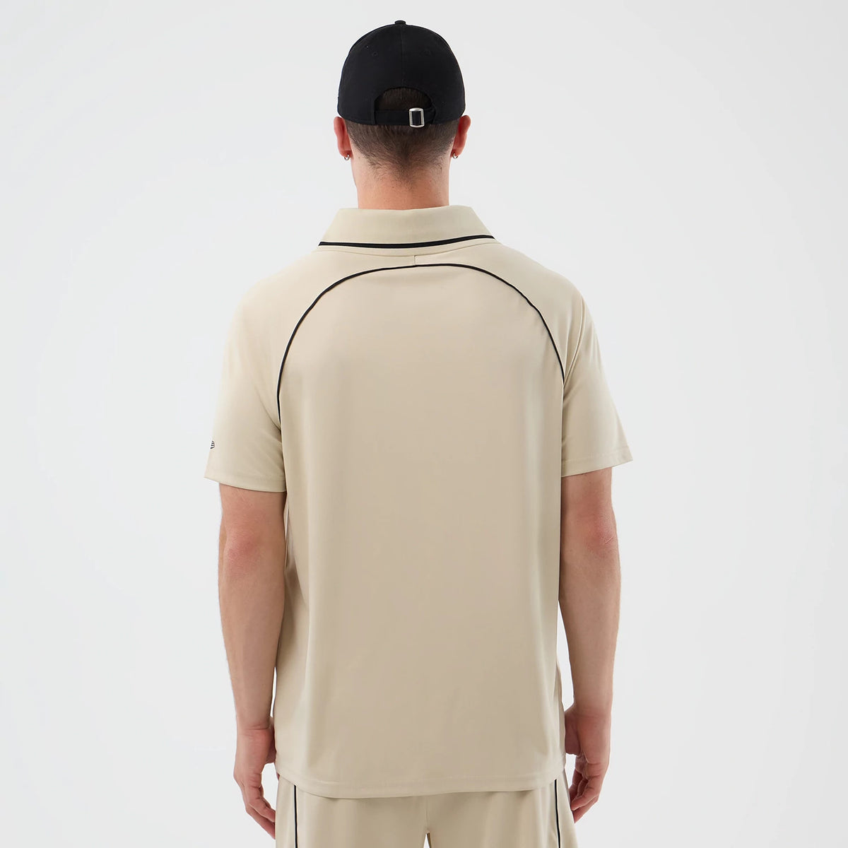 New Era Football Light Beige T-Shirt, back view on a model, featuring a clean light beige design with black piping outlining the shoulder seam and collar, short sleeves and a small embroidered New Era logo on the left sleeve.