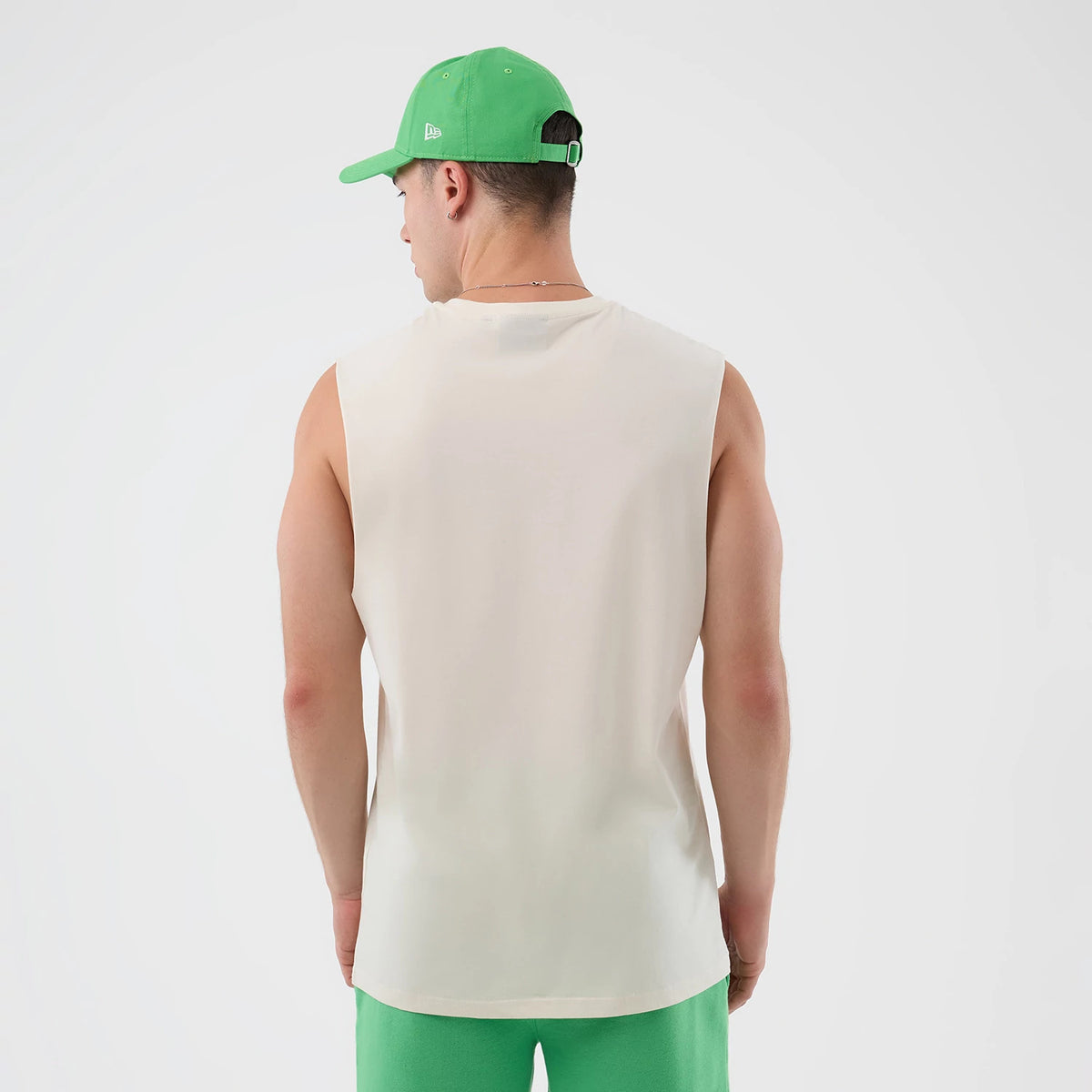 New Era LA Dodgers MLB League Essential Open White Vest, back view on a model wearing a green cap and shorts, showing the plain white back of the sleeveless vest and the relaxed fit over the shoulders.