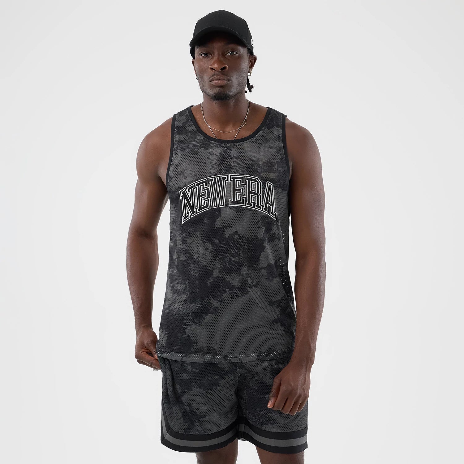 The model is wearing this New Era All Over Print Mesh Tank Top in black camo. 1