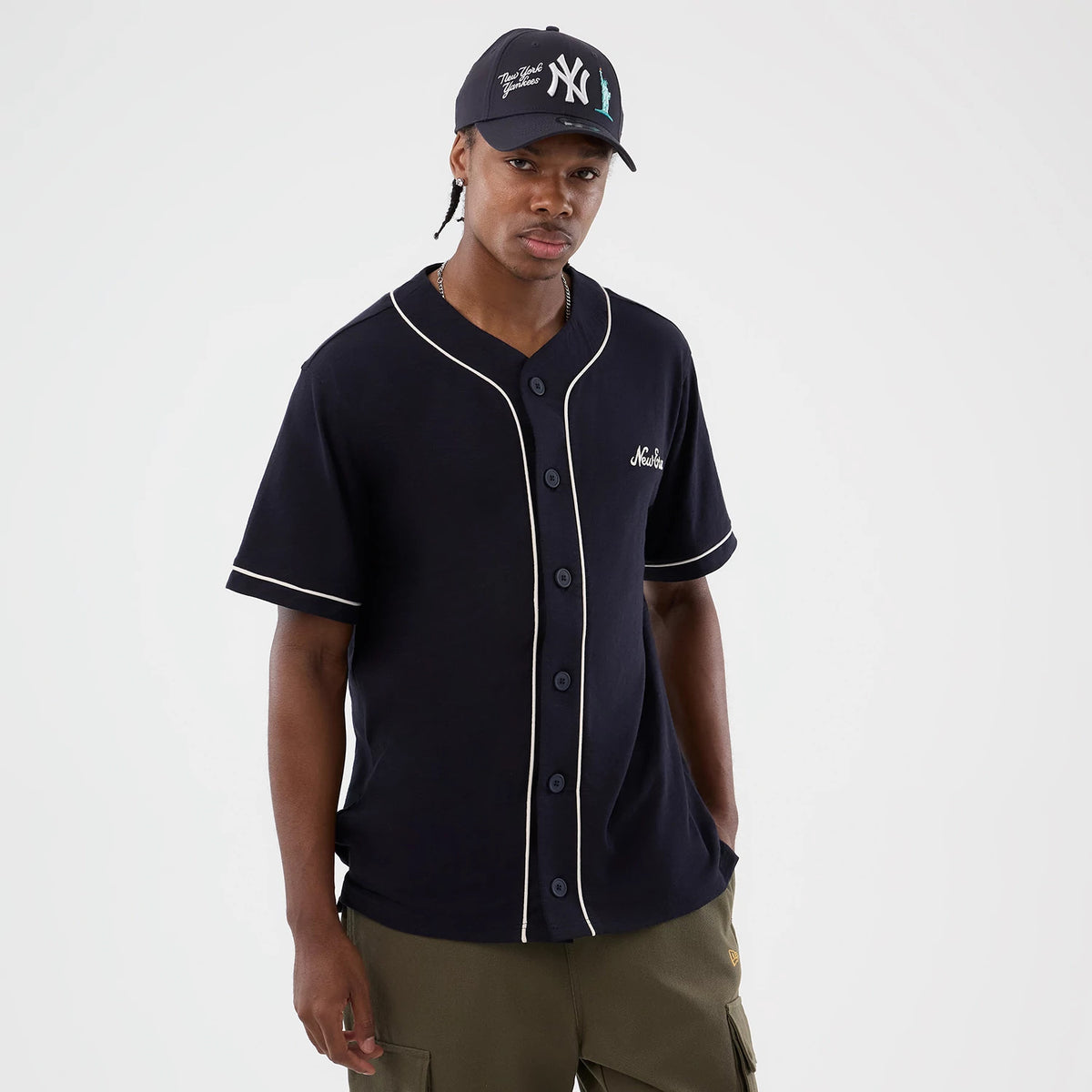 New Era Slub Navy Baseball Jersey, front view on a model with contrasting white piping along the button placket and sleeves, featuring a script logo on the left chest and short sleeves for a classic sportswear look.