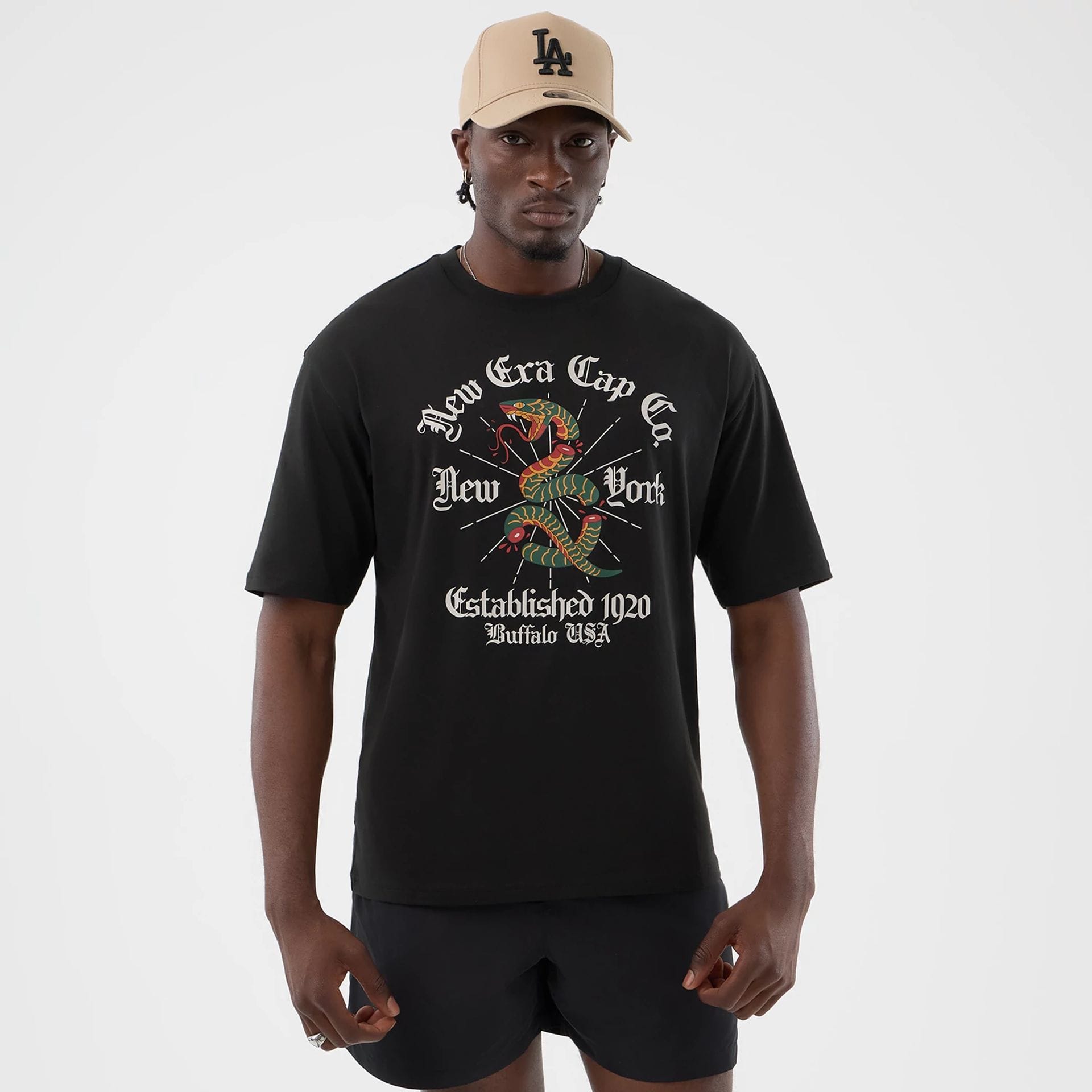The model is wearing this New Era Serpent Graphic Oversized T-Shirt in black. 1