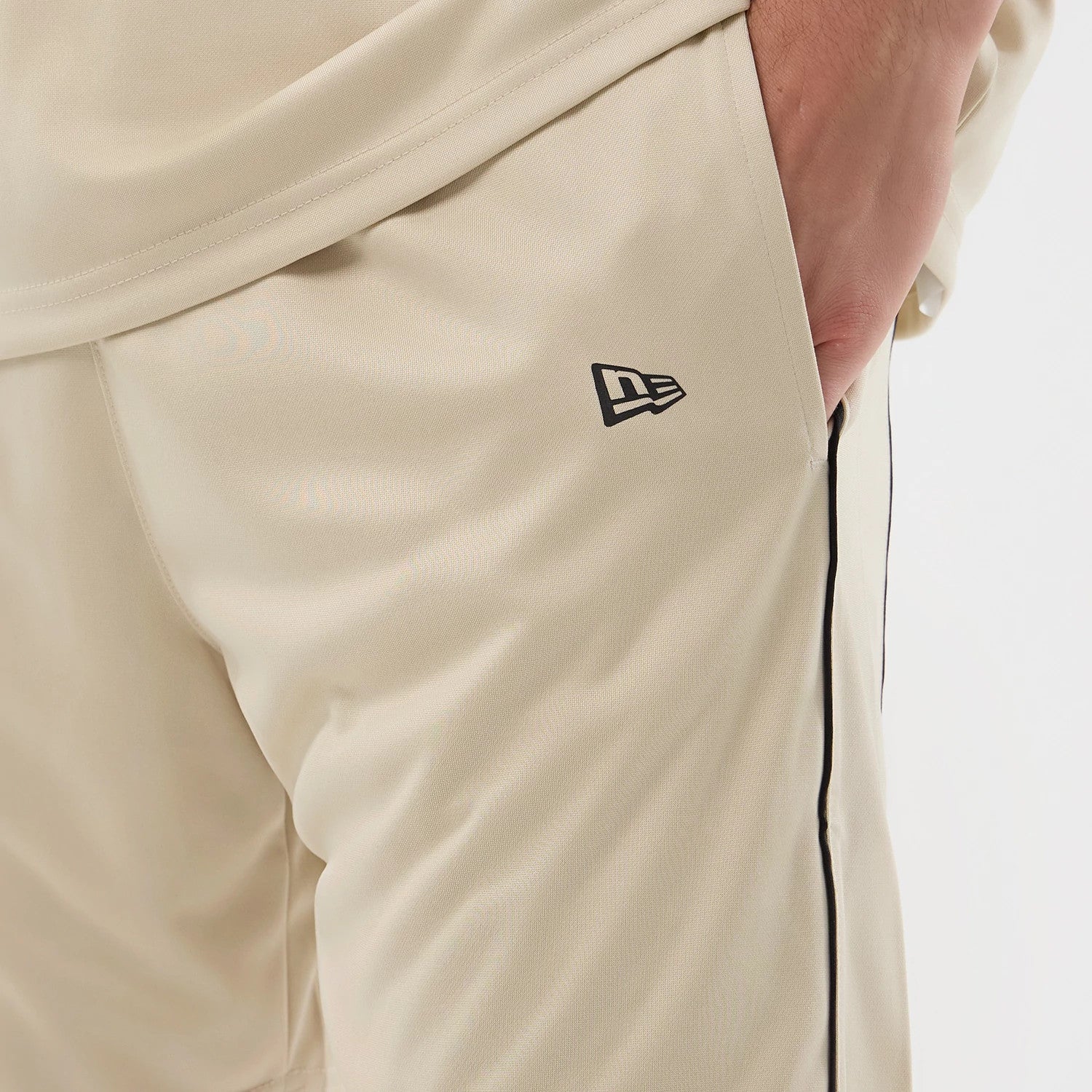 The model is wearing these New Era Football Shorts in light beige. 4