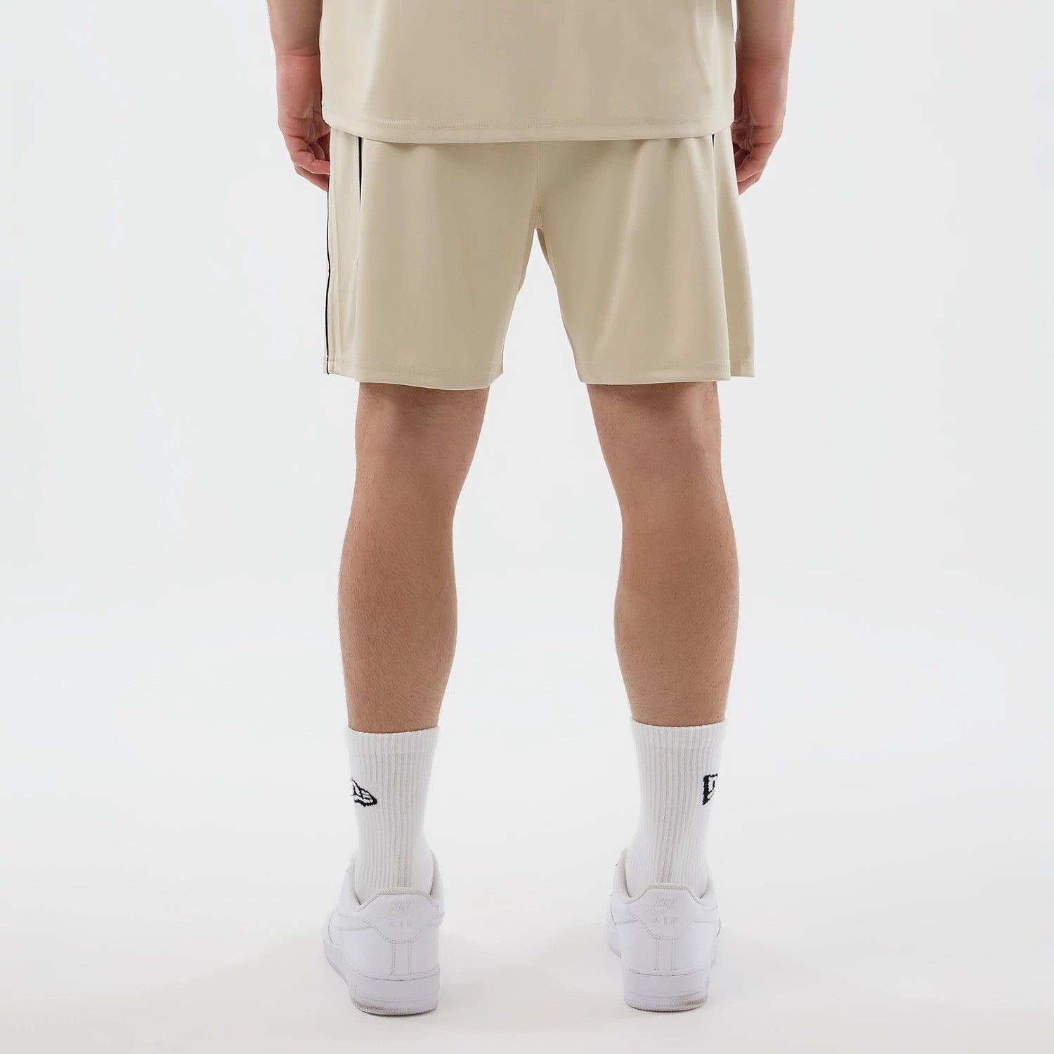 The model is wearing these New Era Football Shorts in light beige. 2
