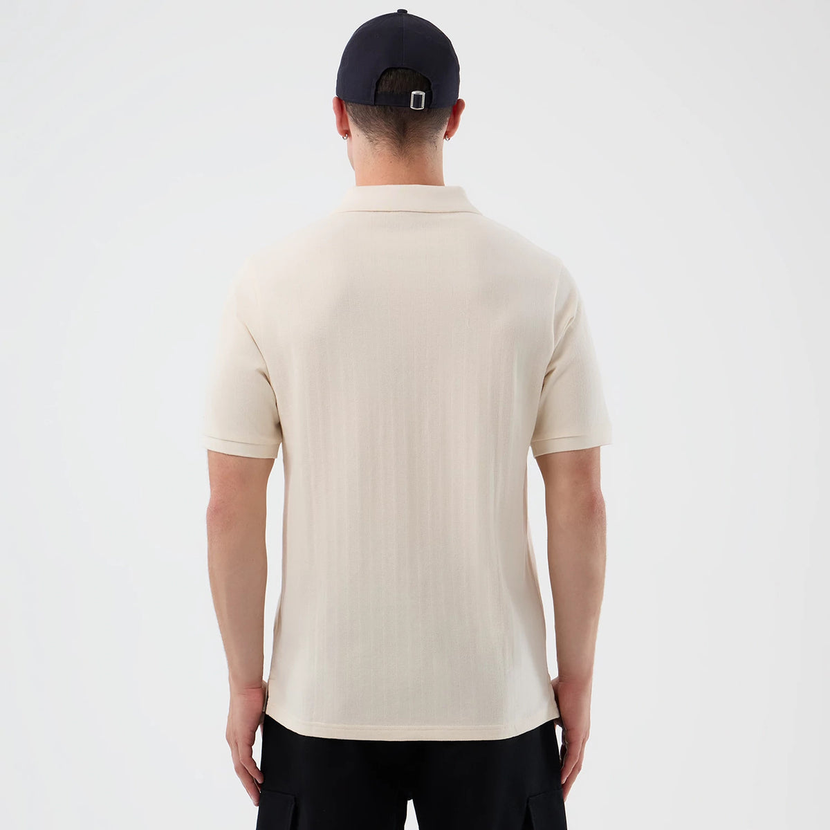 New Era LA Dodgers MLB Rib Open White Polo T-Shirt, back view on a model featuring a light cream design with short sleeves and a ribbed texture, paired with a dark cap, highlighting the simplicity and casual elegance of the polo shirt.