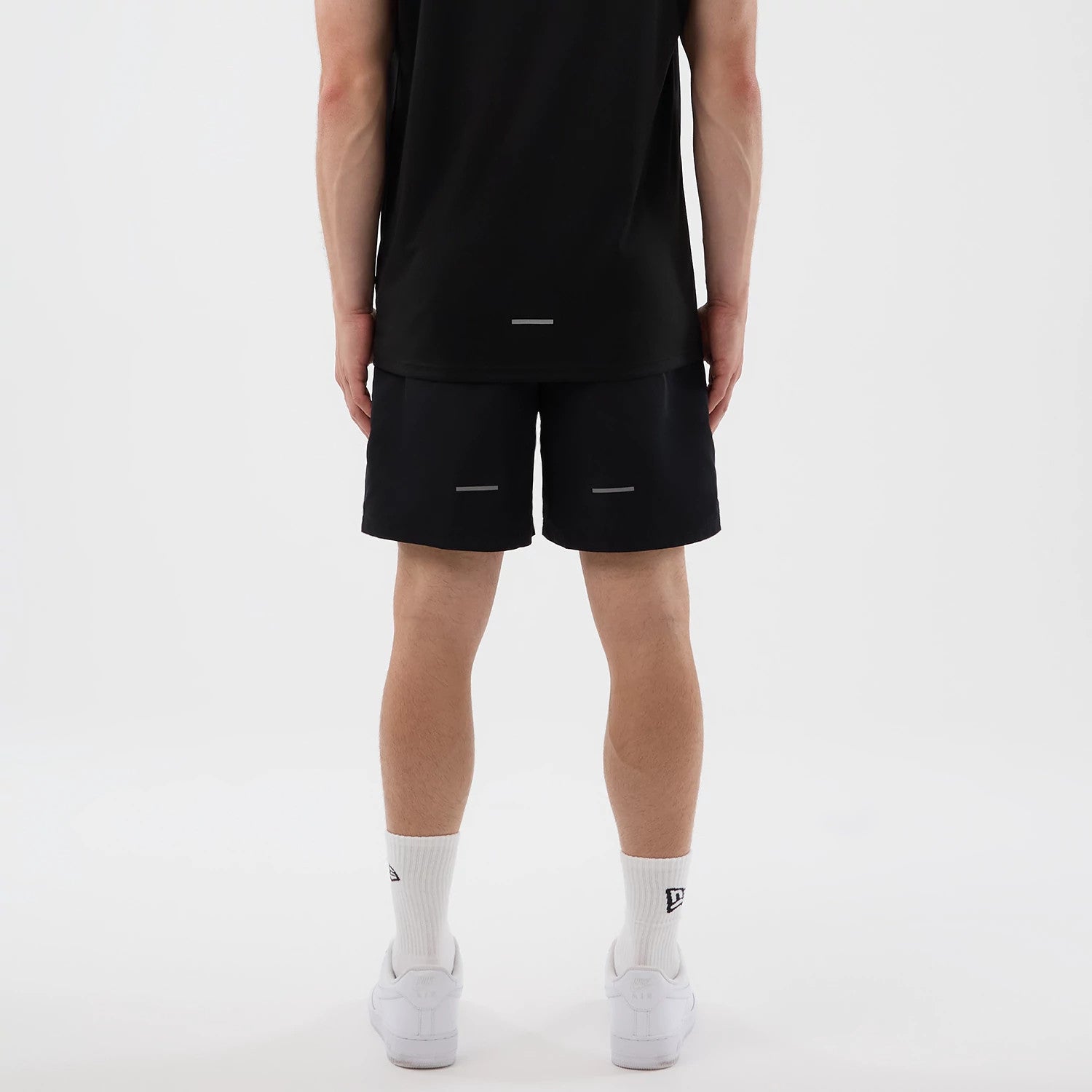 New Era New York Yankees MLB Core Plus Black Shorts, back view on a model with a plain black t-shirt and white trainers, featuring reflective strips on each leg and a simple design that emphasises functionality and minimalist style.