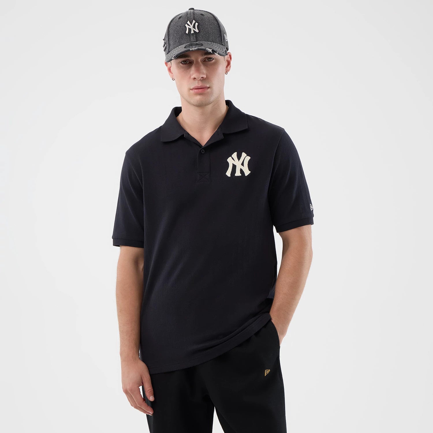 New Era New York Yankees MLB Rib Navy Polo T-Shirt, front view on a model wearing a matching cap, featuring the white embroidered NY logo on the left chest, a classic polo collar, and a small New Era logo on the sleeve.
