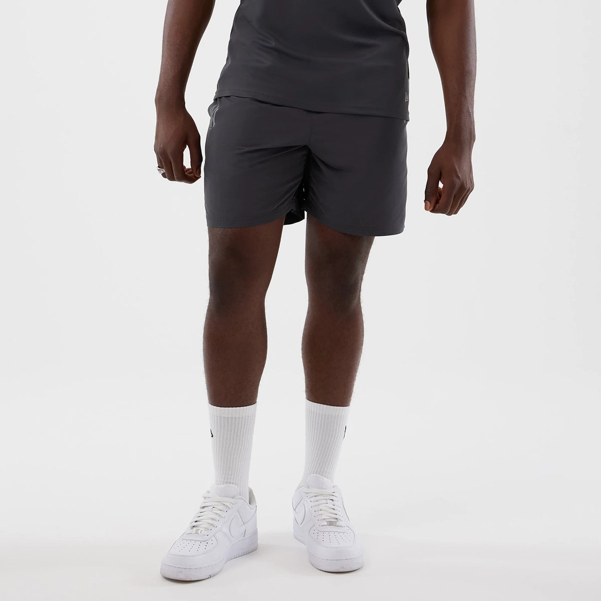 New Era New York Yankees MLB Core Plus Dark Grey Shorts, front view on-model showing the plain dark grey shorts, mid-thigh length with a relaxed fit, styled with a matching top and white trainers, no logos or graphic elements.