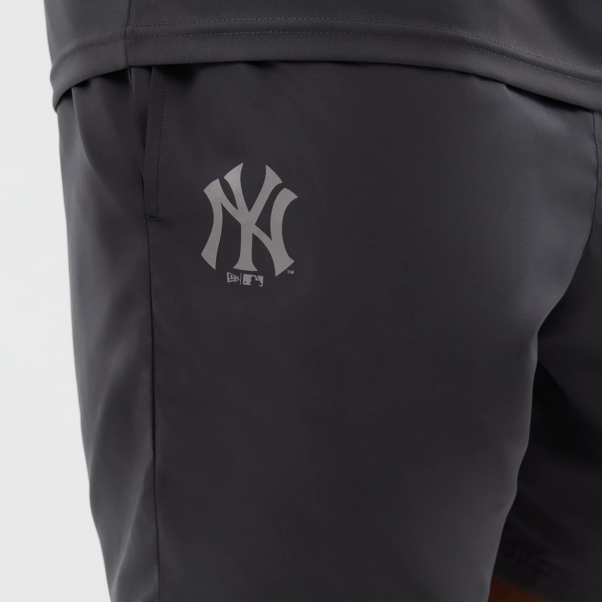 New Era New York Yankees MLB Core Plus Dark Grey Shorts, side view featuring a printed New York Yankees logo on the upper leg, a dark grey finish, and an elasticated waistband at the top of the shorts.