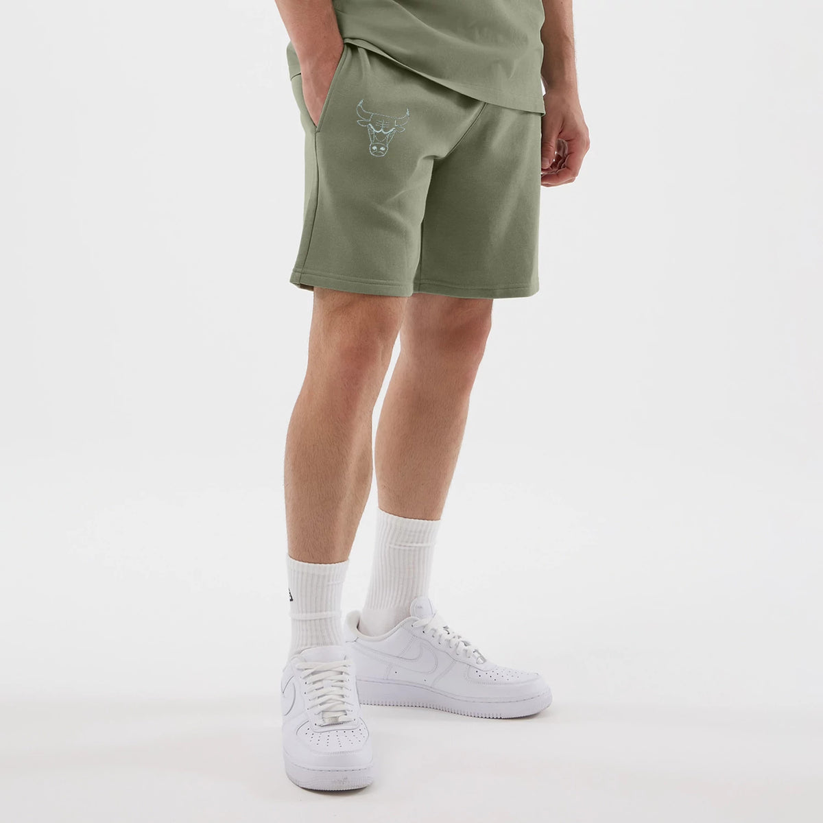 New Era Chicago Bulls NBA League Essential Pastel Green Shorts, on-model view showing embroidered Chicago Bulls logo on the left leg, loose fit above the knee, paired with high white socks and white trainers on the model.