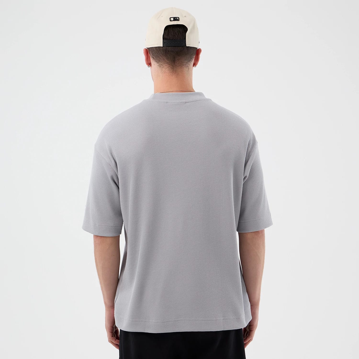 New Era New York Mets MLB Waffle Grey T-Shirt, back view on a model showing the textured waffle pattern across the light grey fabric, loose short sleeves and a plain design with a relaxed fit, complemented by a lightly structured collar.