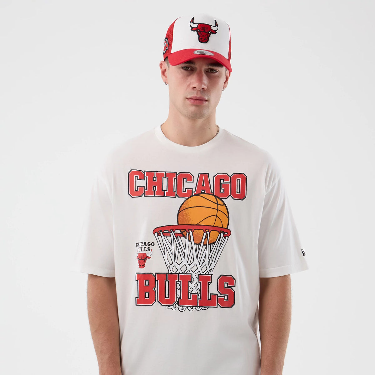 New Era Chicago Bulls NBA Basketball Graphic White Oversized T-Shirt, front view on-model highlighting a large graphic of a basketball in a hoop with Chicago Bulls lettering in red above and below, and a small embroidered New Era logo on the sleeve.
