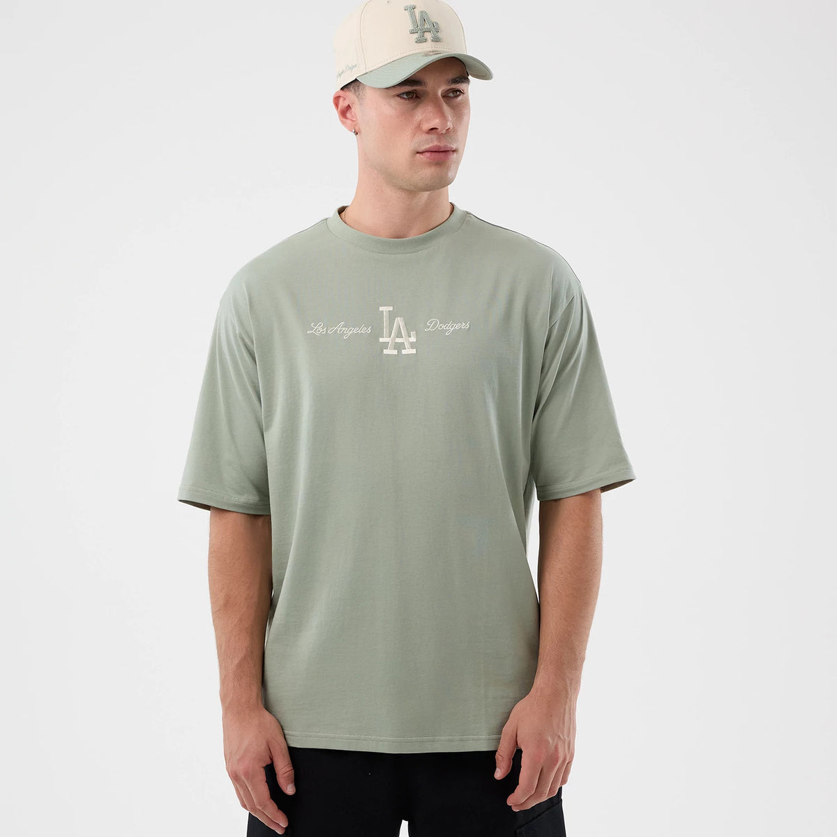 New Era LA Dodgers MLB Script Pastel Green Oversized T-Shirt, front view on-model showcasing an embroidered white LA Dodgers logo centred on the chest. The model wears a matching cap, creating a cohesive casual look.