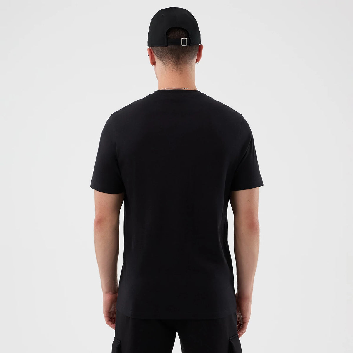 New Era Chicago Bulls NBA Court Graphic Black T-Shirt, back view on a model wearing a matching black cap, showing the plain black surface of the t-shirt with a straight hem and short sleeves, and the cap featuring an adjustable back strap.