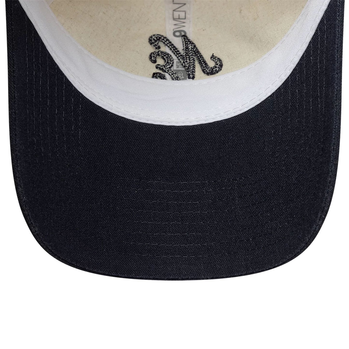 Womens New Era Linen Navy 9TWENTY Adjustable Cap, inside view showing the natural coloured sweatband beneath a navy visor, with a New Era tag and intricate black embroidery on the lining against the beige fabric.