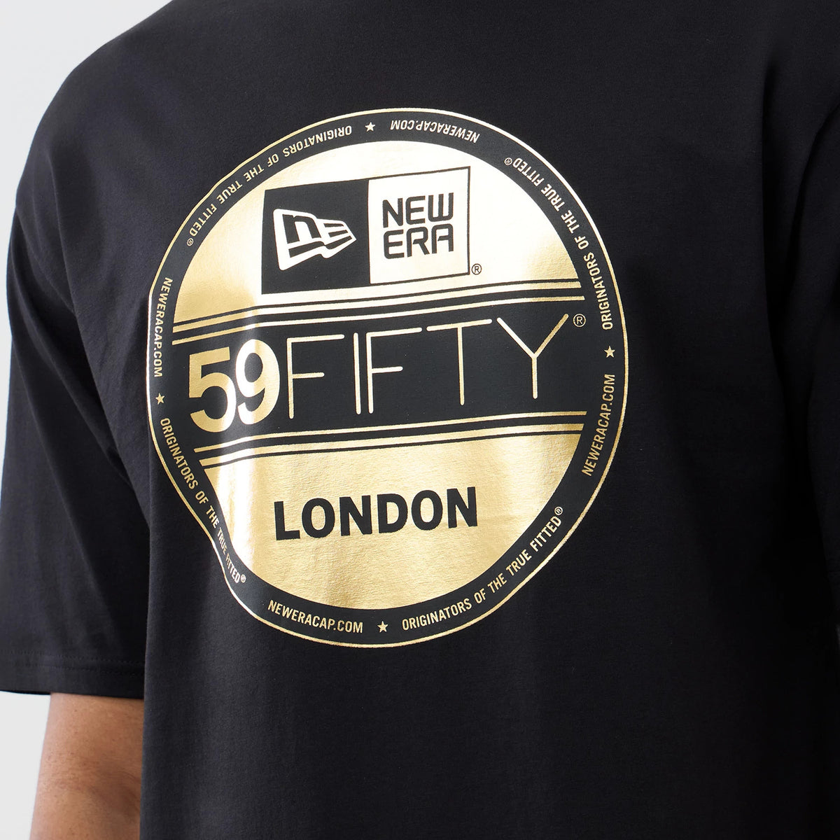 New Era Sticker London Black Oversized T-Shirt, front view showing a large gold printed New Era 59FIFTY sticker design, featuring New Era branding and the word LONDON in letters, centre chest on a black background.