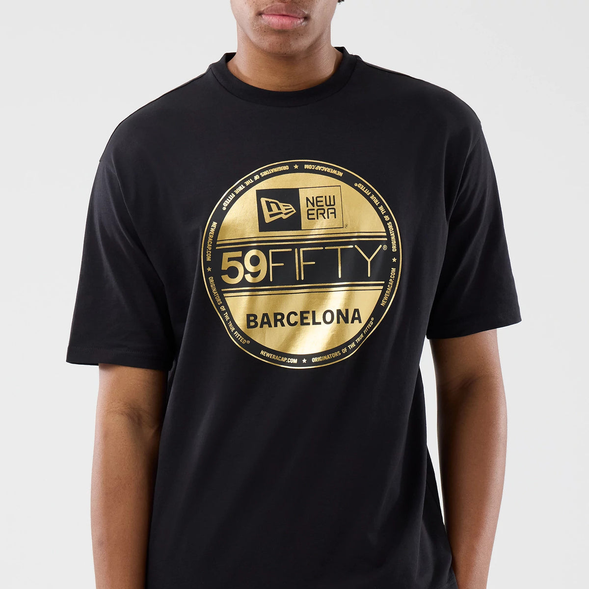 New Era Sticker Barcelona Black Oversized T-Shirt, front view on-model displaying a large gold printed 59FIFTY graphic with New Era logo and Barcelona text centred on the chest, featuring a relaxed fit with short sleeves and a high crew neckline.