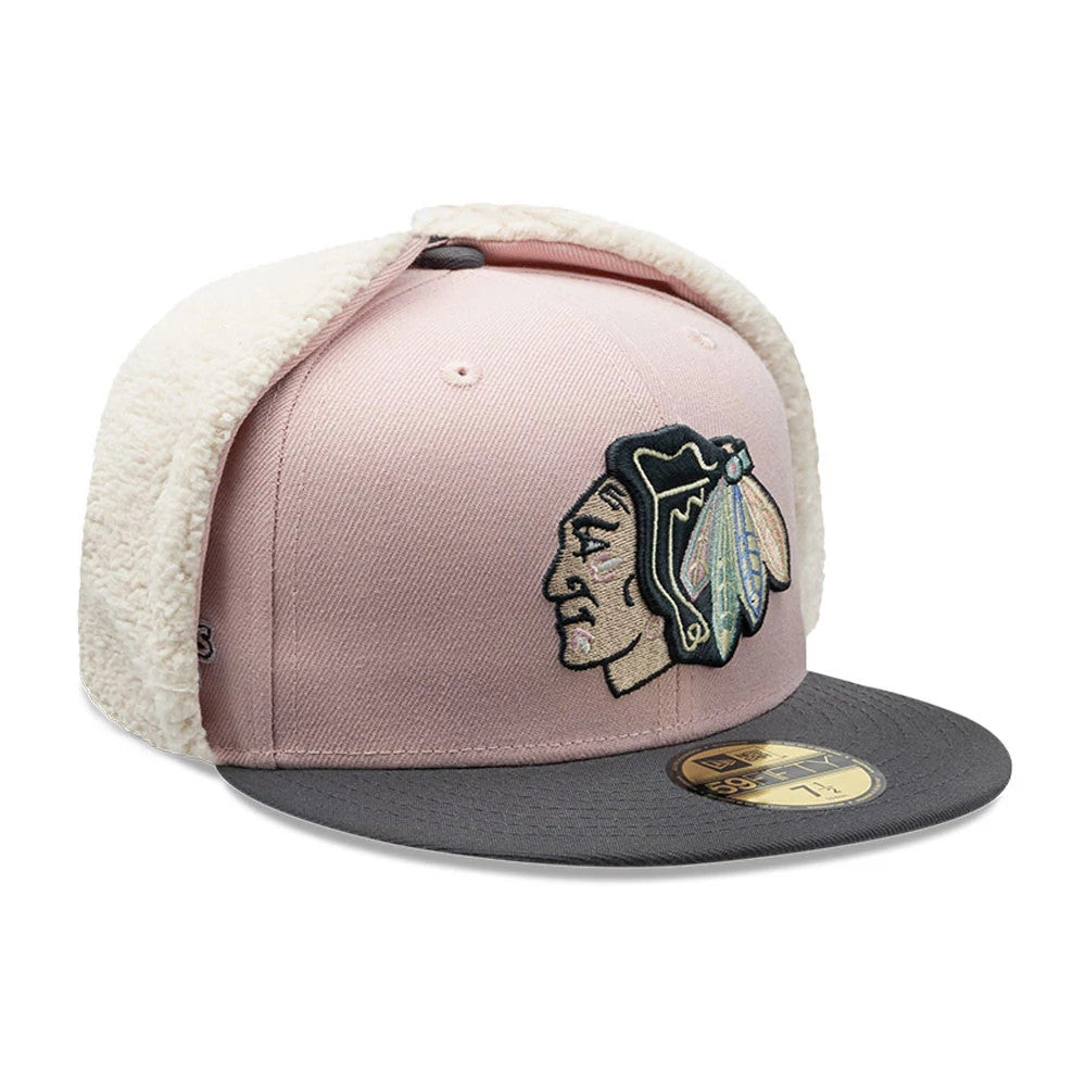 Chicago Blackhawks NHL Patch Pastel Pink New Era 59FIFTY Fitted Cap, three-quarter view showing the detailed embroidered team logo on the front panel, grey flat visor with a gold 59FIFTY size sticker, and cream fleece-lined dogears folded upwards.