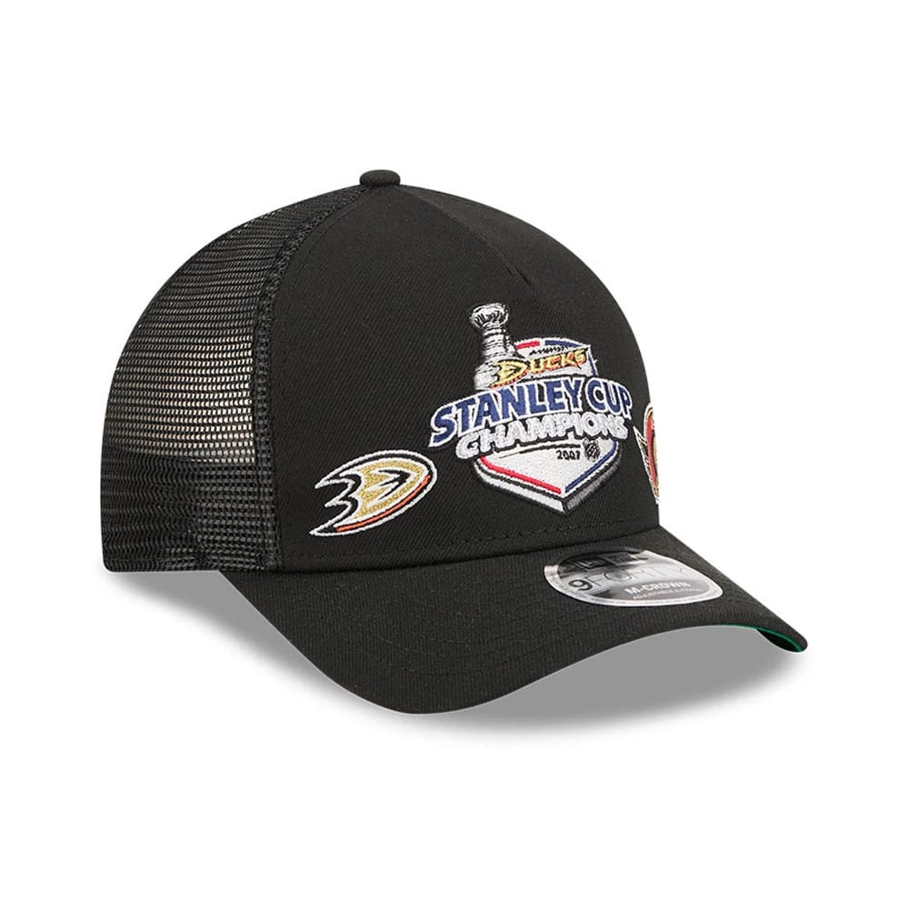 Ducks NHL Stanley Cup Black New Era 9FORTY M-Crown A-Frame Trucker Adjustable Cap, three-quarter view showing the embroidered Stanley Cup Champions graphic and Ducks logo on the front panel, black mesh back panels.